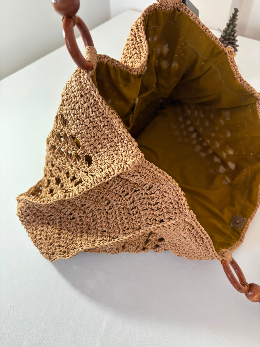 Unique handcrafted raffia purse featuring durable crochet construction and decorative wooden handles.