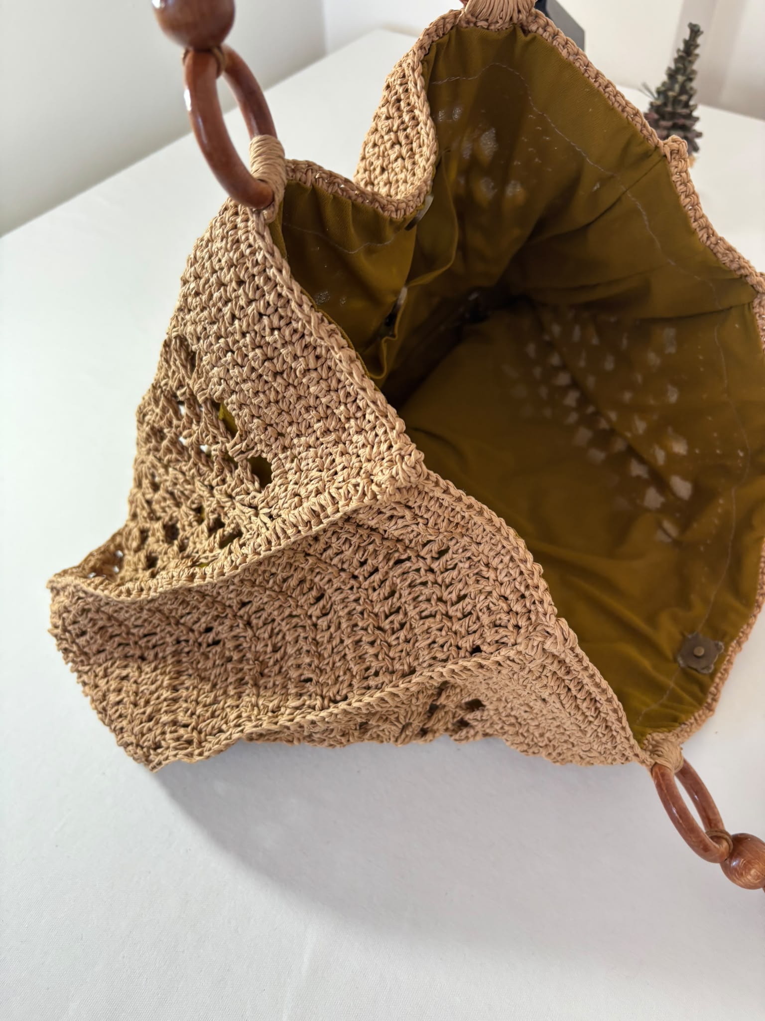 Unique handcrafted raffia purse featuring durable crochet construction and decorative wooden handles.